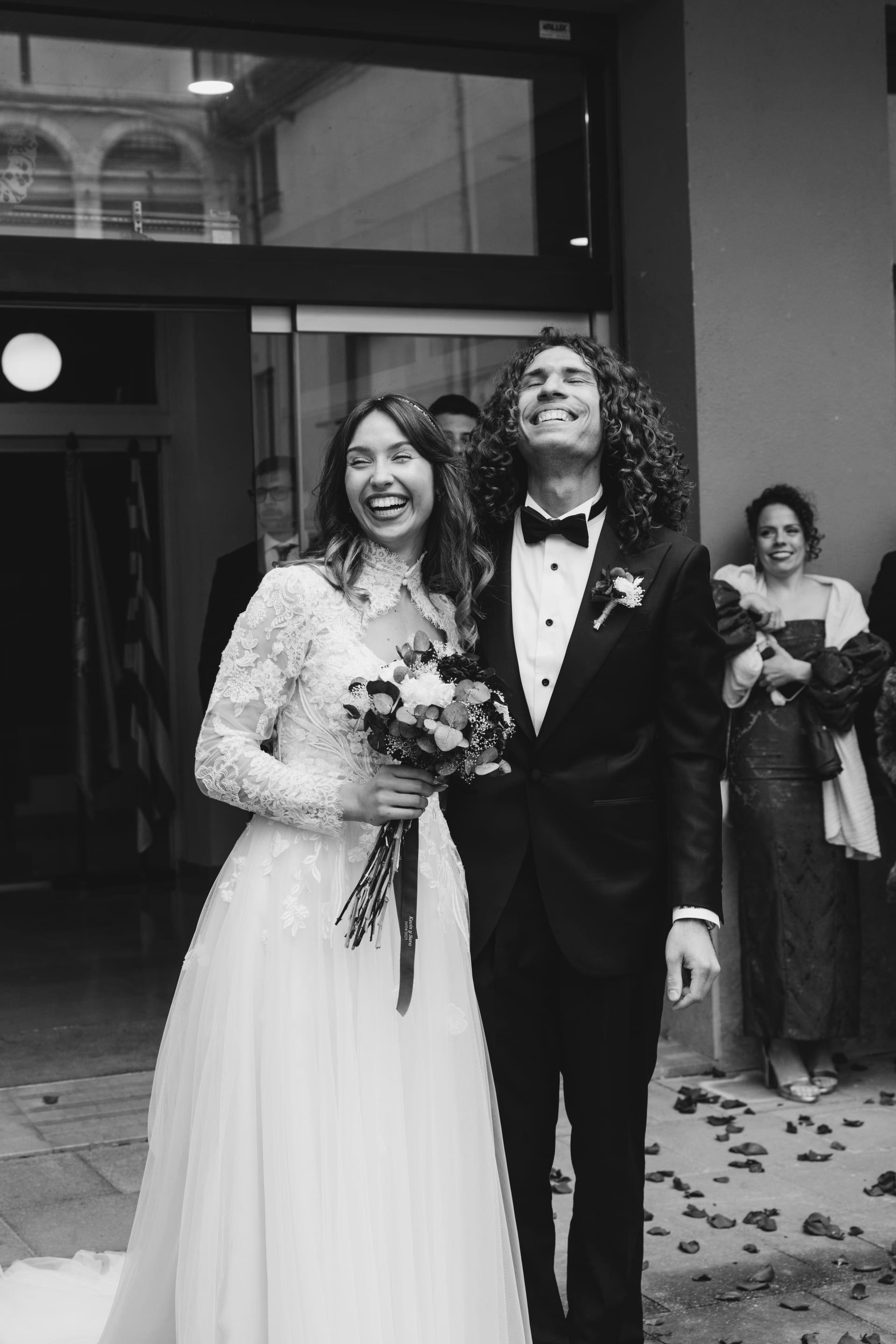 La pareja entre los invitados, con los pétalos todavía en el suelo