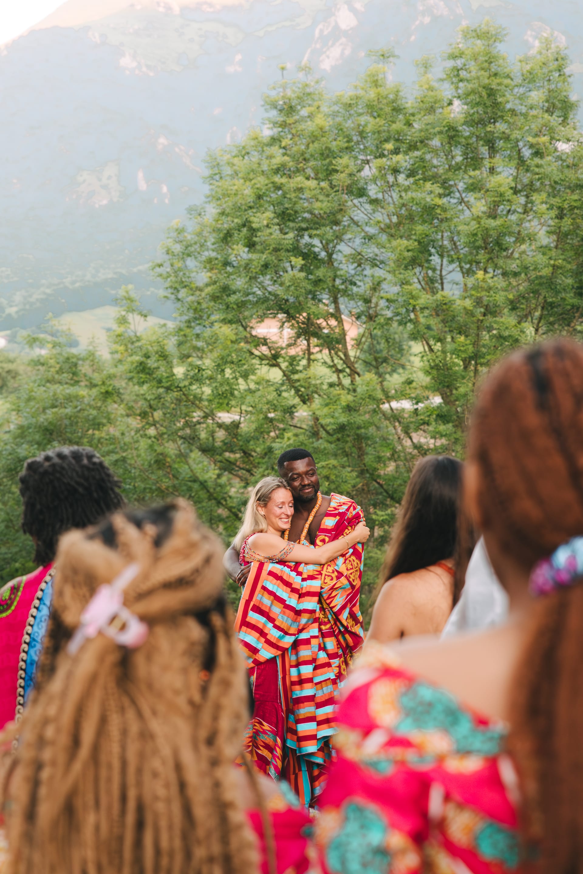 Invitadas con vestidos ghaneses de colores y trenzas, con la montaña al fondo