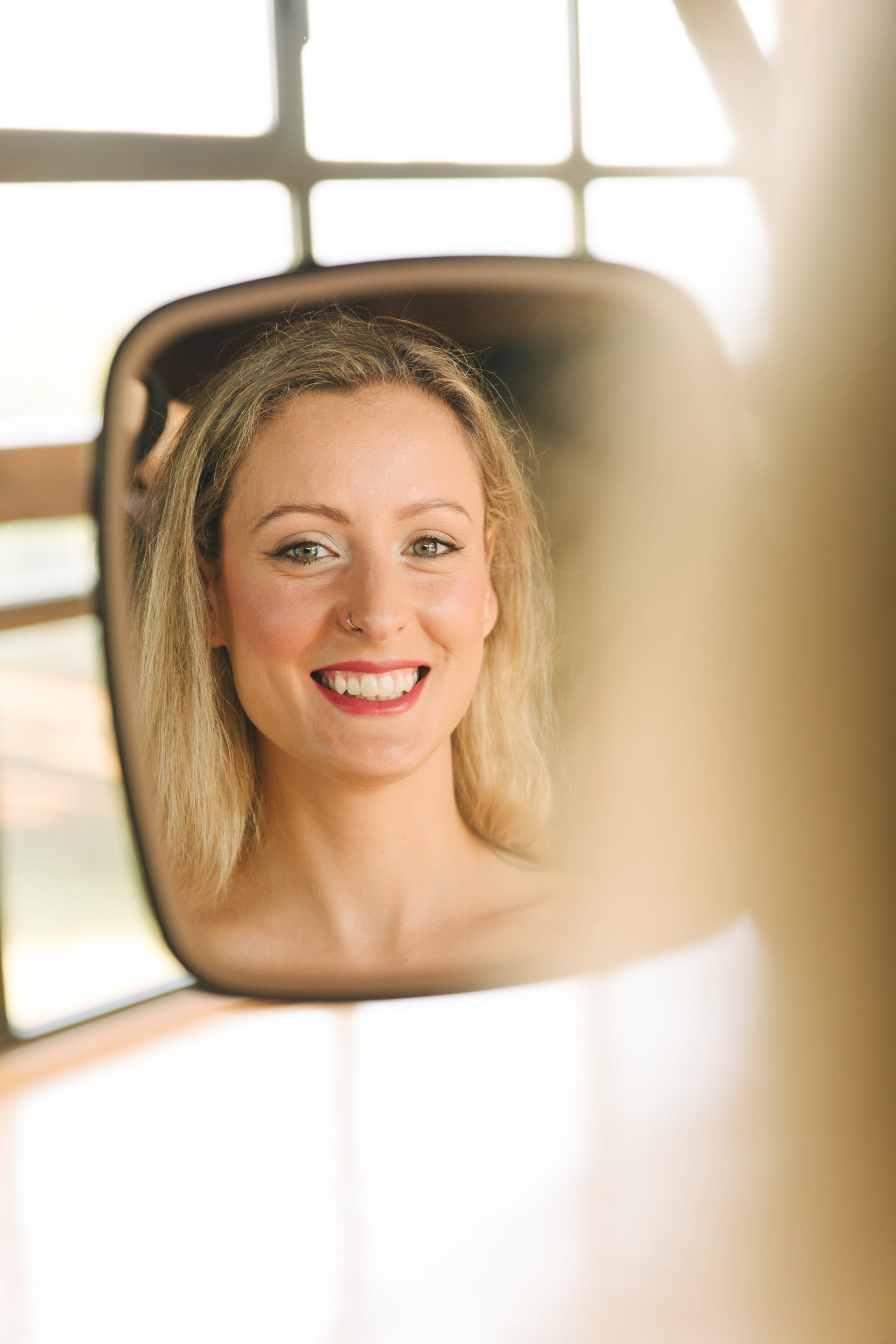 El reflejo de la novia sonriendo en un espejo pequeño