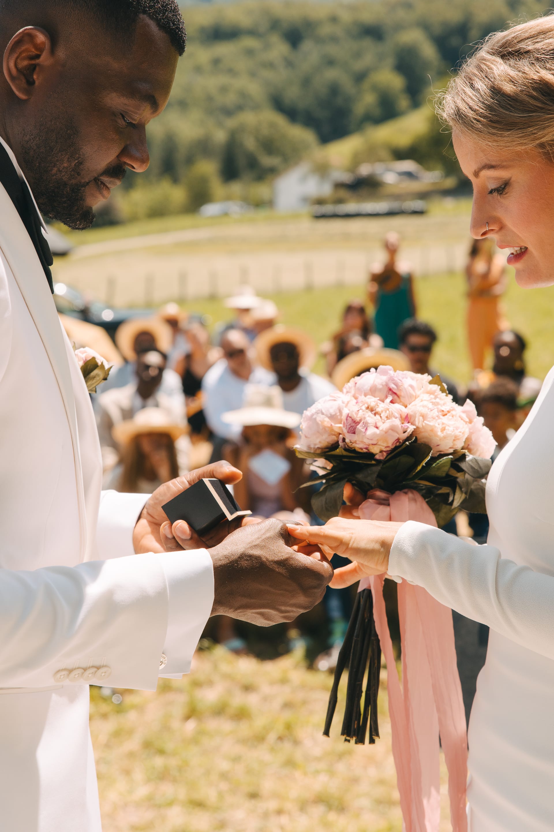 El novio poniendo el anillo a la novia con los invitados detrás