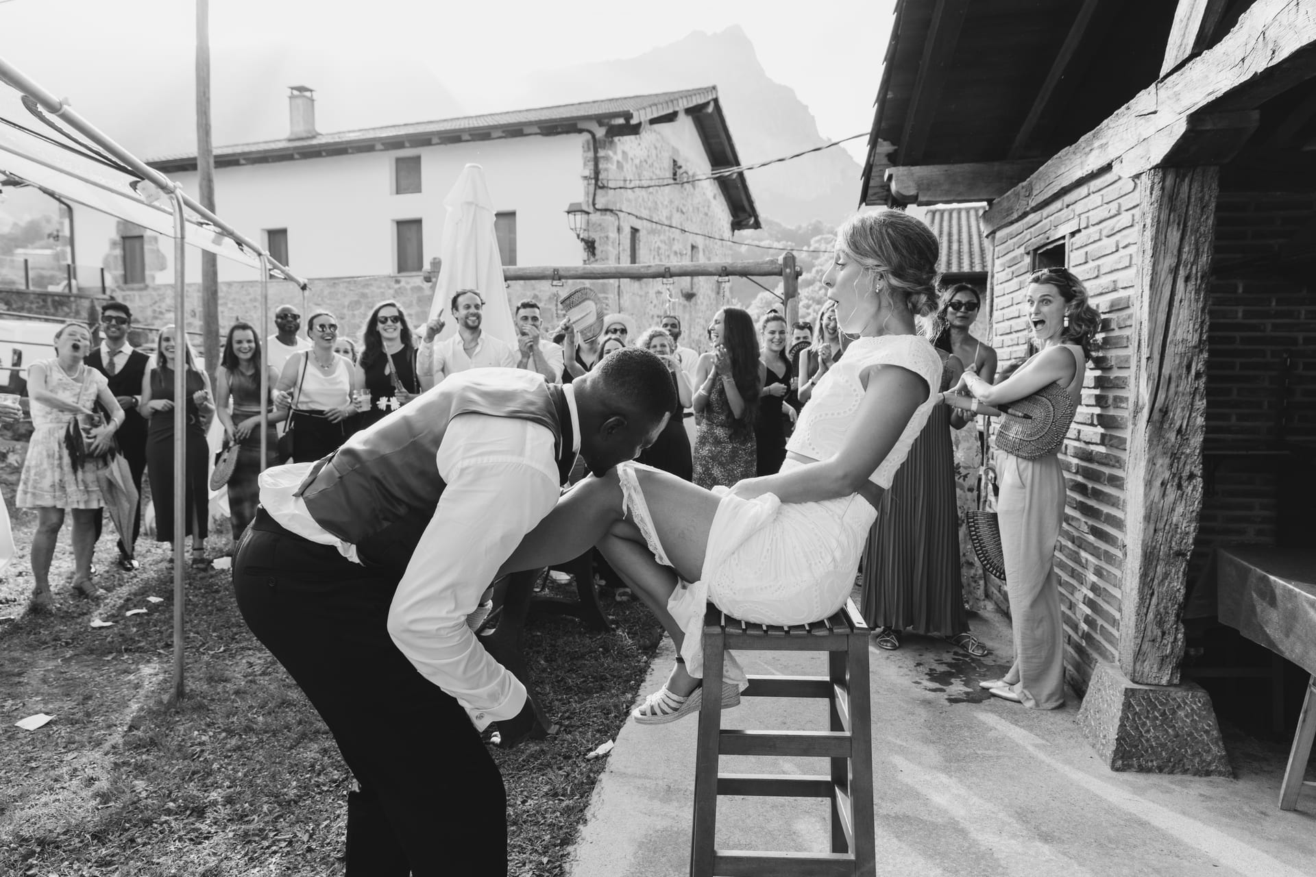 Invitados jugando con una silla en mitad de la calle del pueblo, en blanco y negro