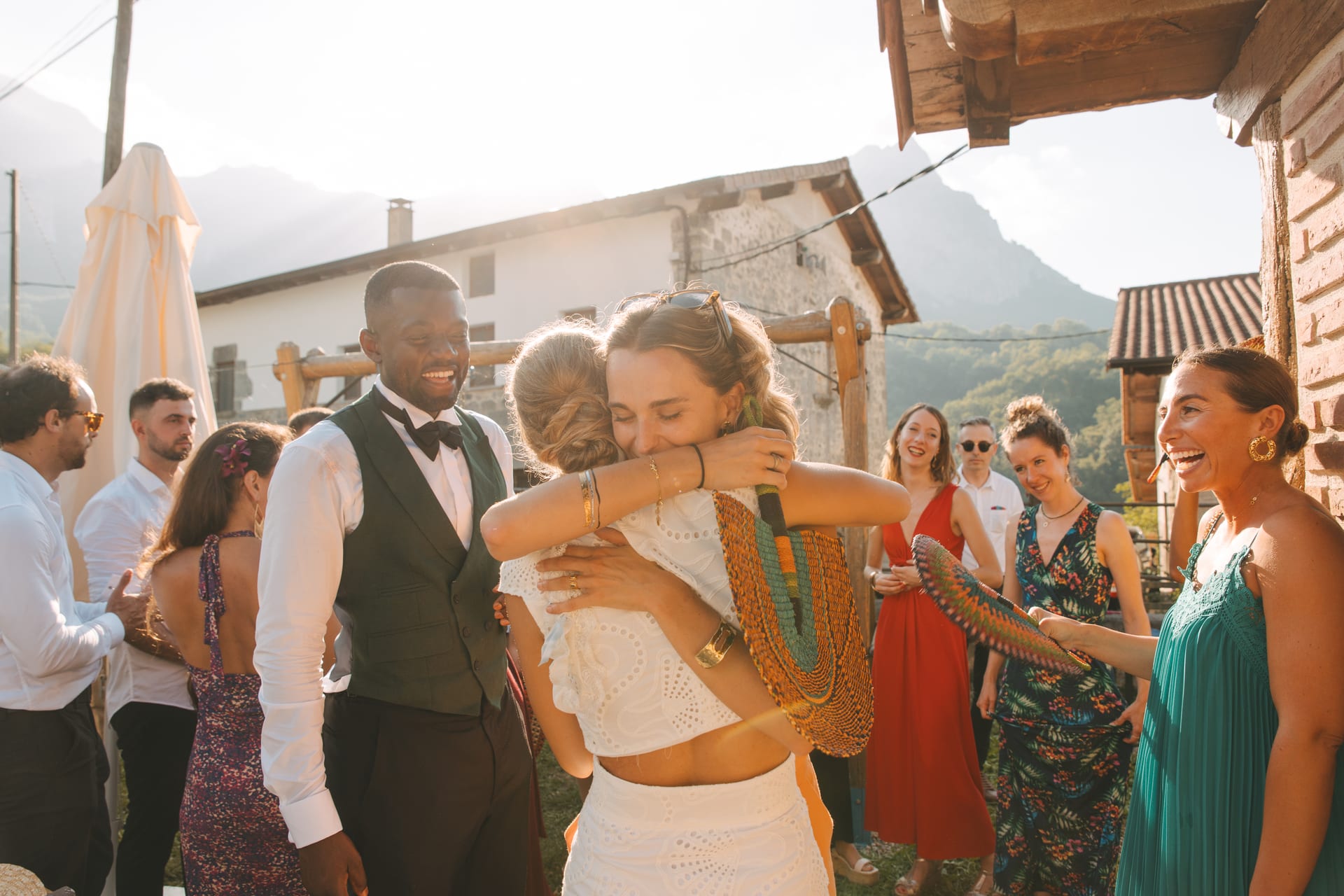 Un abrazo entre invitados rodeados de amigos, con las montañas al fondo