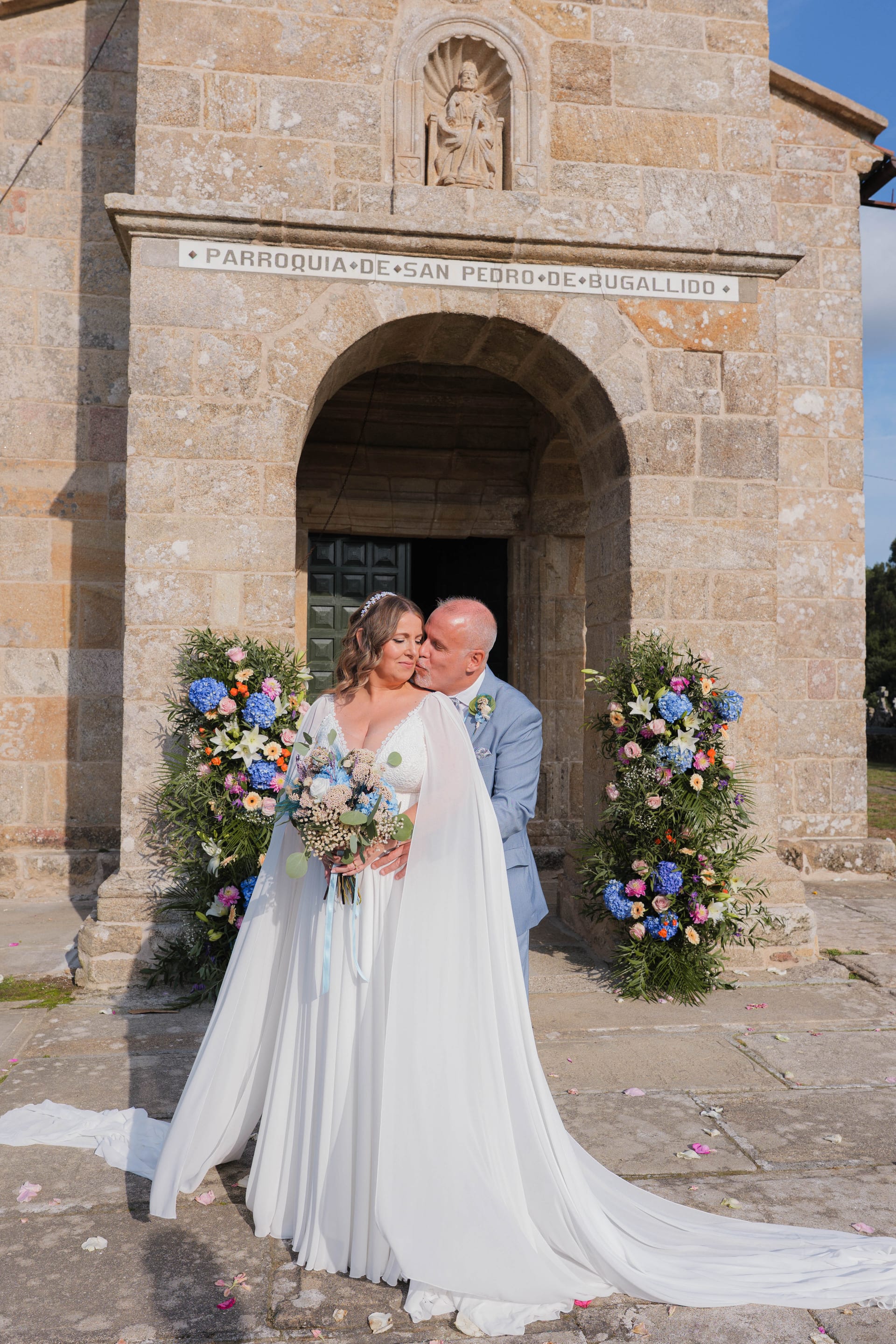 Los novios ante la fachada de San Pedro de Bugallido